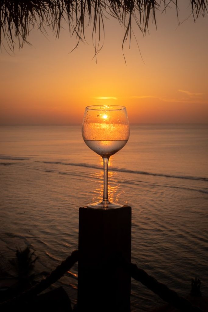 A wineglass silhouette against a stunning Bali sunset over the ocean, capturing tropical serenity.